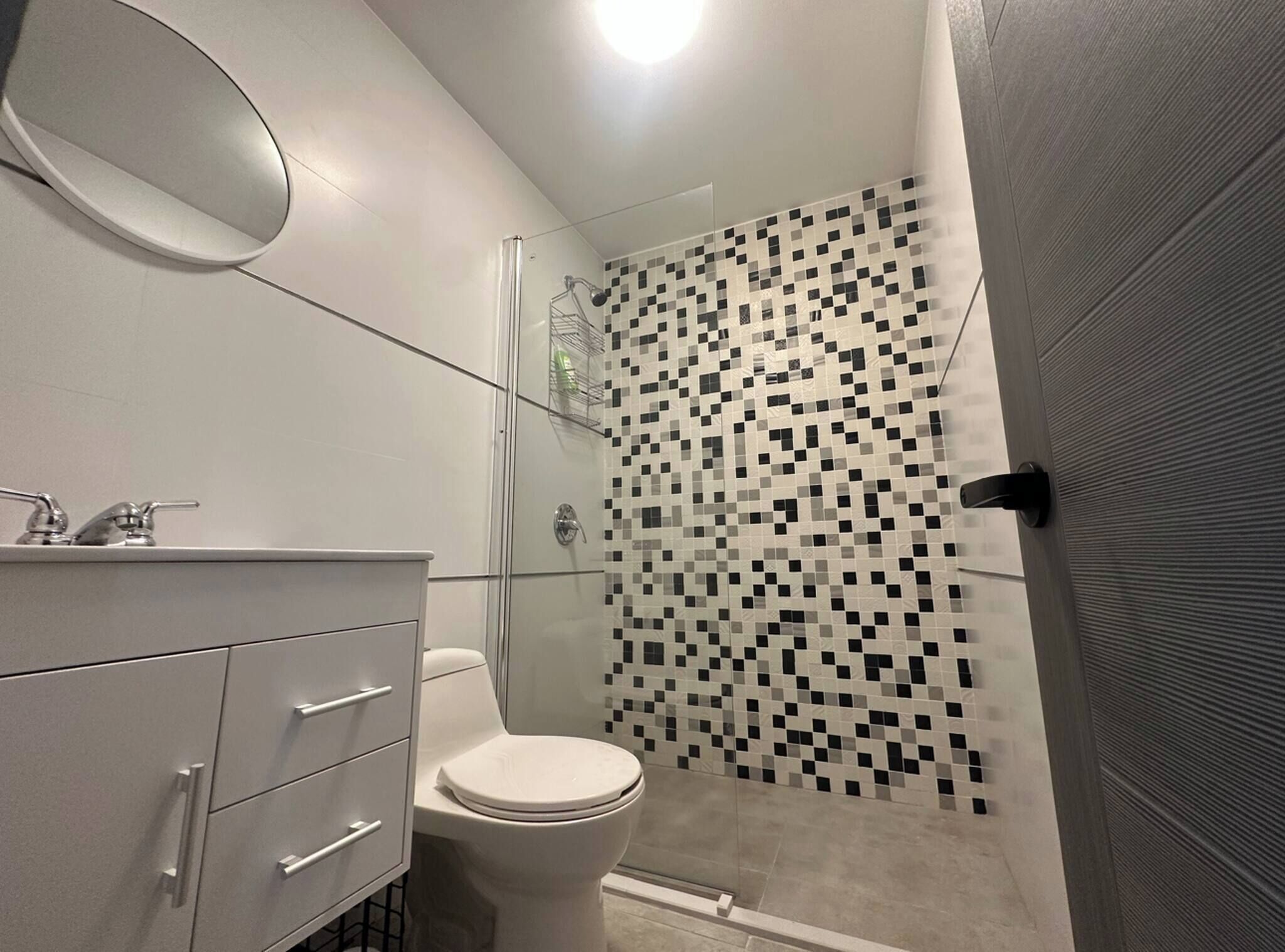 A modern bathroom with a glass-enclosed shower, a white toilet, and a vanity with drawers.