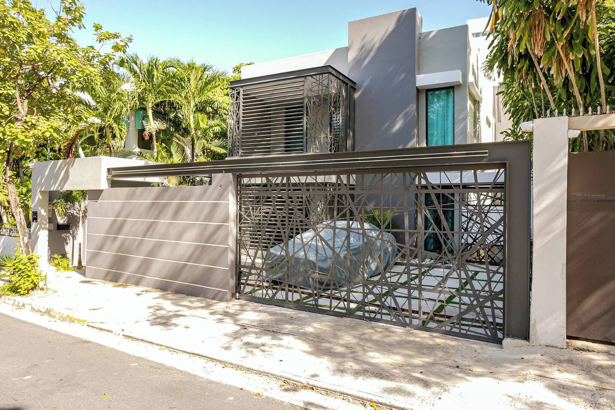 A modern building with a metal gate, a large air conditioning unit, and a view of the street.