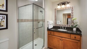 A bathroom with a glass-enclosed shower, a sink with a wooden vanity, and a mirror with a decorative frame. - Charming 1-bedroom villa in Palm Desert. Close to Coachella Music Festival (Palm Desert)