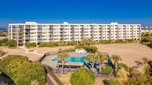 A multi-story hotel with a pool area, surrounded by greenery and a clear blue sky. - Dune View|Indoor Pool·Beachfront·Hot Tub·AB Condo (Atlantic Beach)