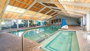 An indoor swimming pool with a glass ceiling, clear poolside area, and a lifeguard chair. - Dune View|Indoor Pool·Beachfront·Hot Tub·AB Condo (Atlantic Beach)
