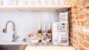 Uma cozinha com cafeteira, café embalado e um recipiente com lanches.