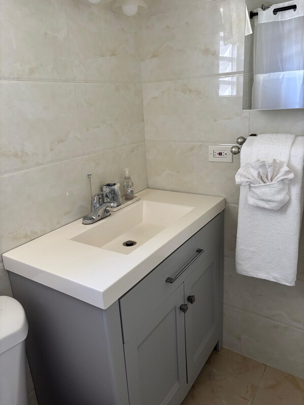 Une salle de bain avec un lavabo blanc, des meubles gris et une serviette blanche suspendue à un porte-serviettes.