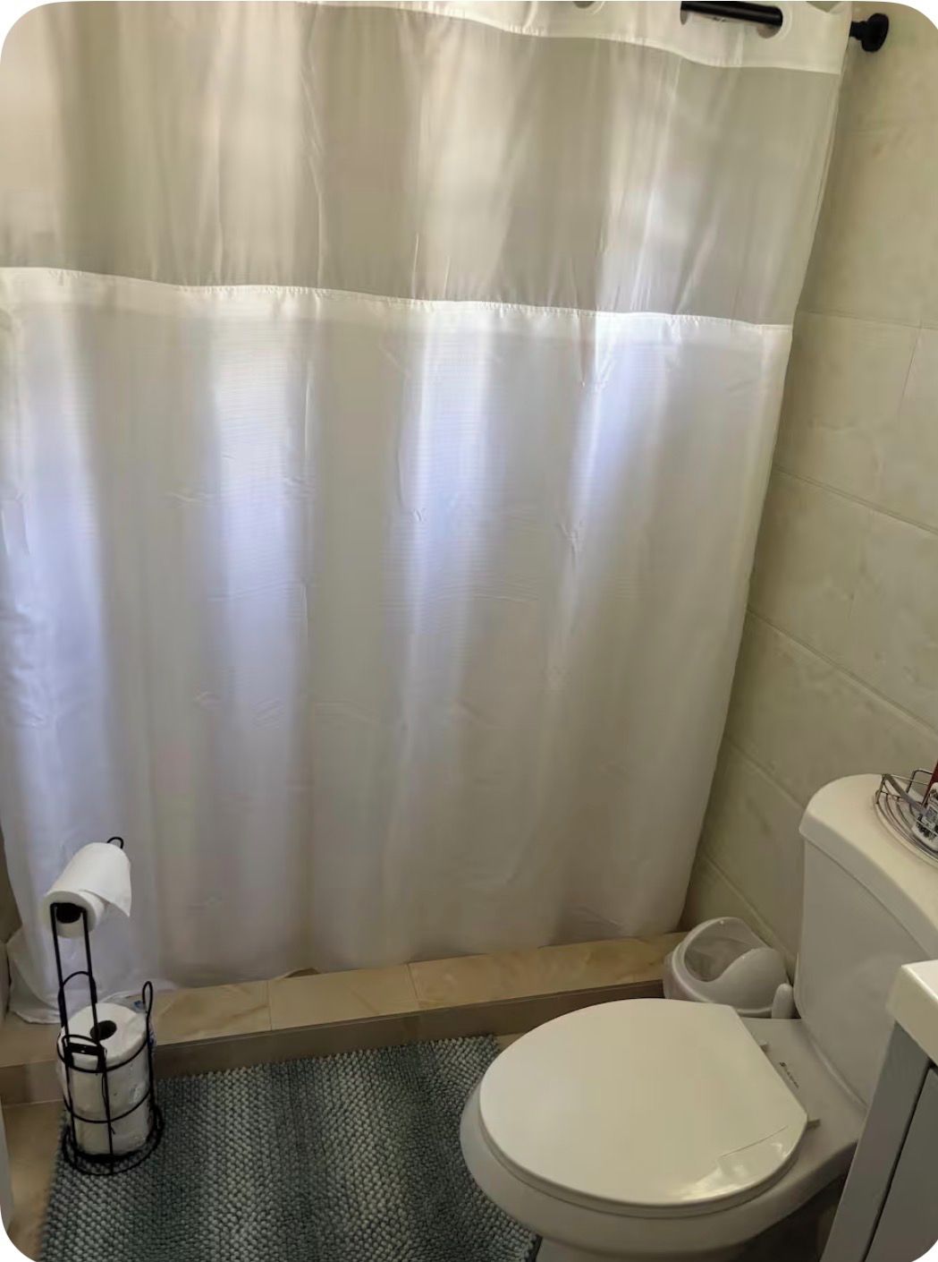 Ein Badezimmer mit Duschvorhang, Toilette und Handtuchhalter mit Handtuch.
