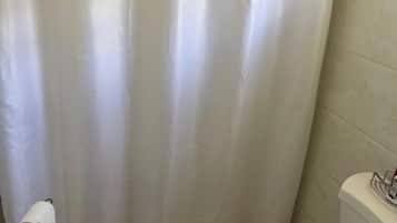Ein Badezimmer mit Duschvorhang, Toilette und Handtuchhalter mit Handtuch.