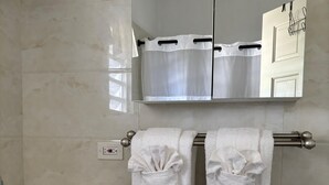 Een badkamer met een witte wastafel, een spiegel en twee handdoeken aan een handdoekrek.