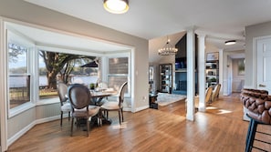 A spacious room with a large dining table, a fireplace, and a view of a lake. - Lakefront Home w/ Game Room & Hot Tub Ponderosa Peninsula by Avantstay (Mooresville)
