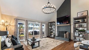 A living room with a fireplace, a sofa, a coffee table, and a bookshelf. - Lakefront Home w/ Game Room & Hot Tub Ponderosa Peninsula by Avantstay (Mooresville)