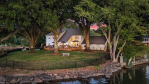 A house with a deck, a lawn, and a pond. - Lakefront Home w/ Game Room & Hot Tub Ponderosa Peninsula by Avantstay (Mooresville)