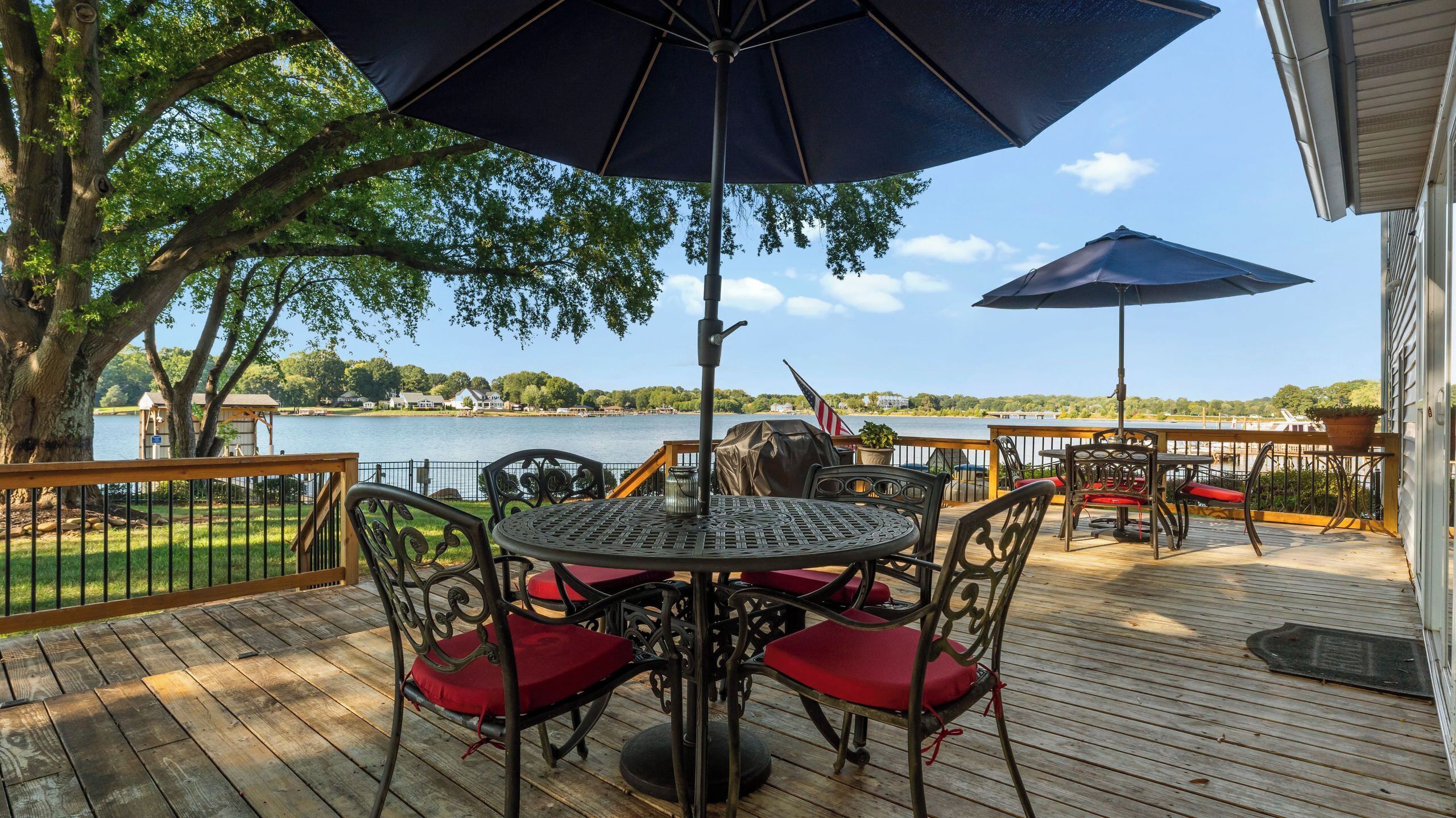 Une terrasse en bois avec une table et des chaises, un parasol et une vue sur un lac.