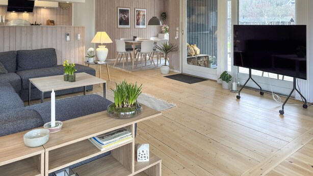 A modern living room with a sofa, coffee table, TV, and a dining area with chairs and a table. - Awesome home in Ebeltoft with WiFi (Ebeltoft)