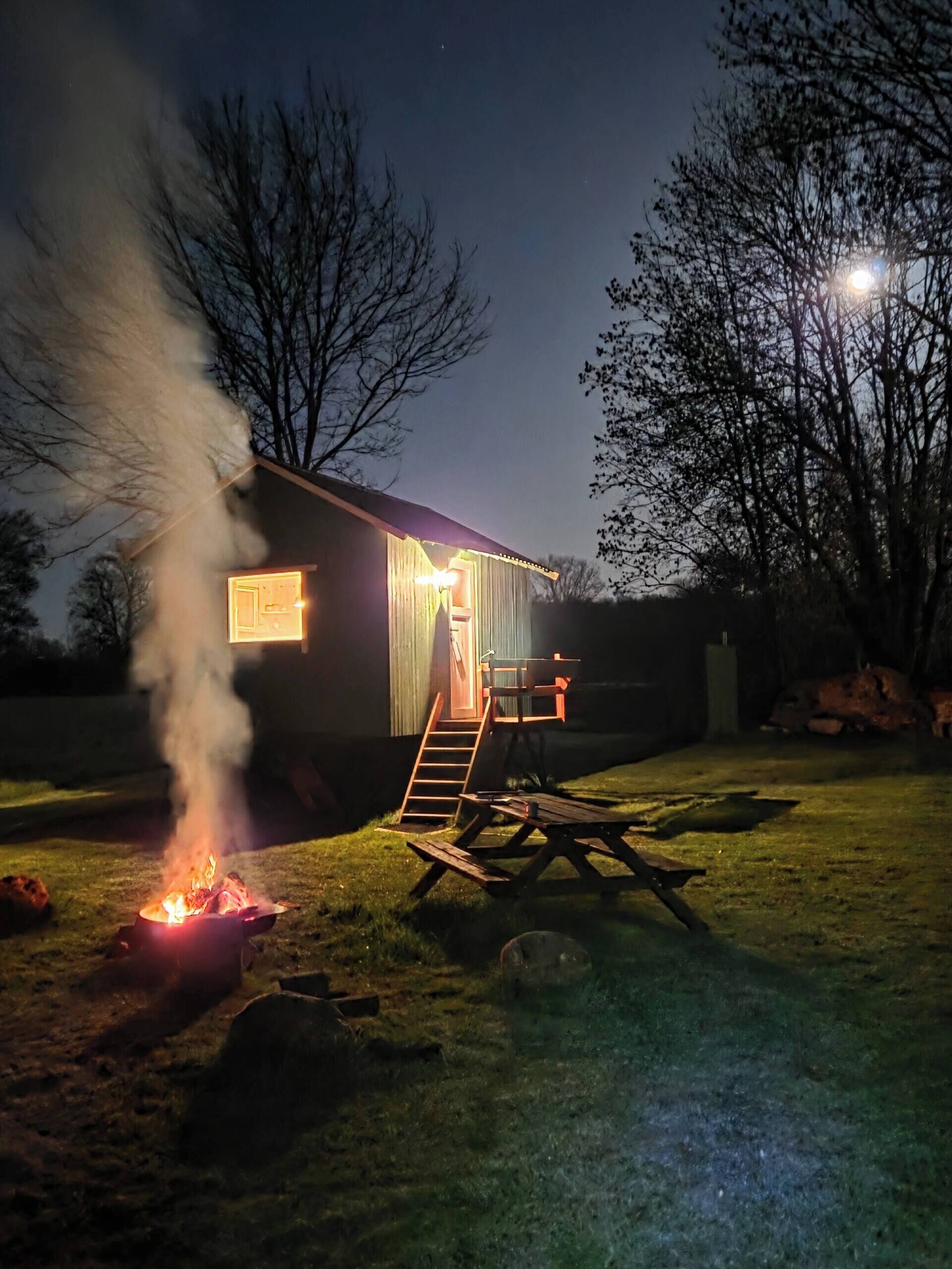 Ett hus med en synlig skorsten som släpper ut rök, en träveranda och en trappa som leder upp till entrén.
