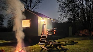 Ett hus med en synlig skorsten som släpper ut rök, en träveranda och en trappa som leder upp till entrén.