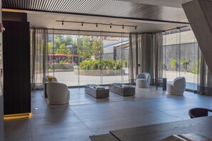 A modern interior with a large glass door leading to a courtyard, a sofa, a coffee table, and a small side table. - AT HOME Alonso (Santiago)
