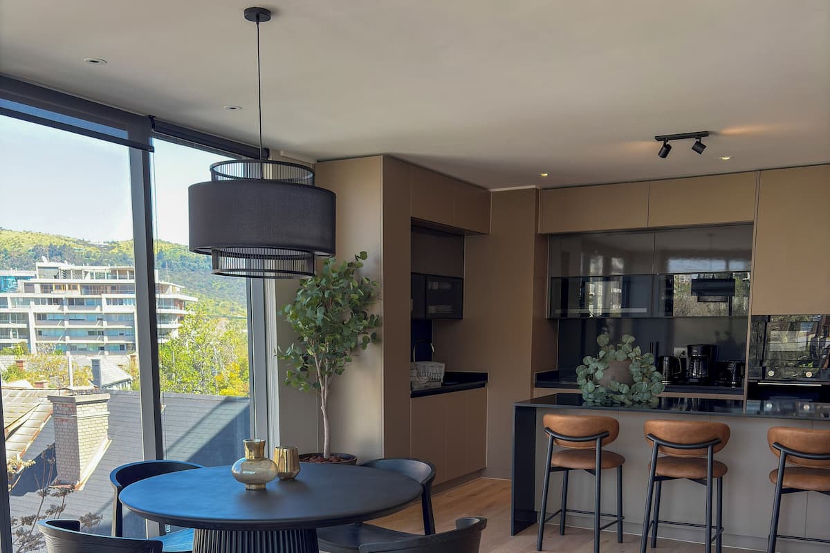 Une cuisine moderne dotée d’un îlot central, de tabourets de bar et d’un coin repas avec une table ronde et des chaises.