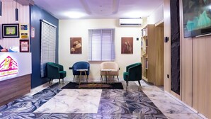 A hotel reception area with a reception desk, three chairs, a window with blinds, and a marble-patterned floor. - H3 Hotel and Events Centre. (Abeokuta)