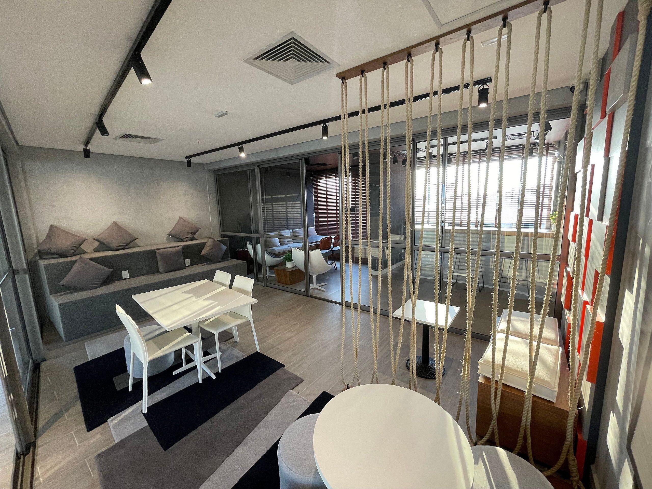 A modern interior with a seating area, a dining table, and a view through large windows.