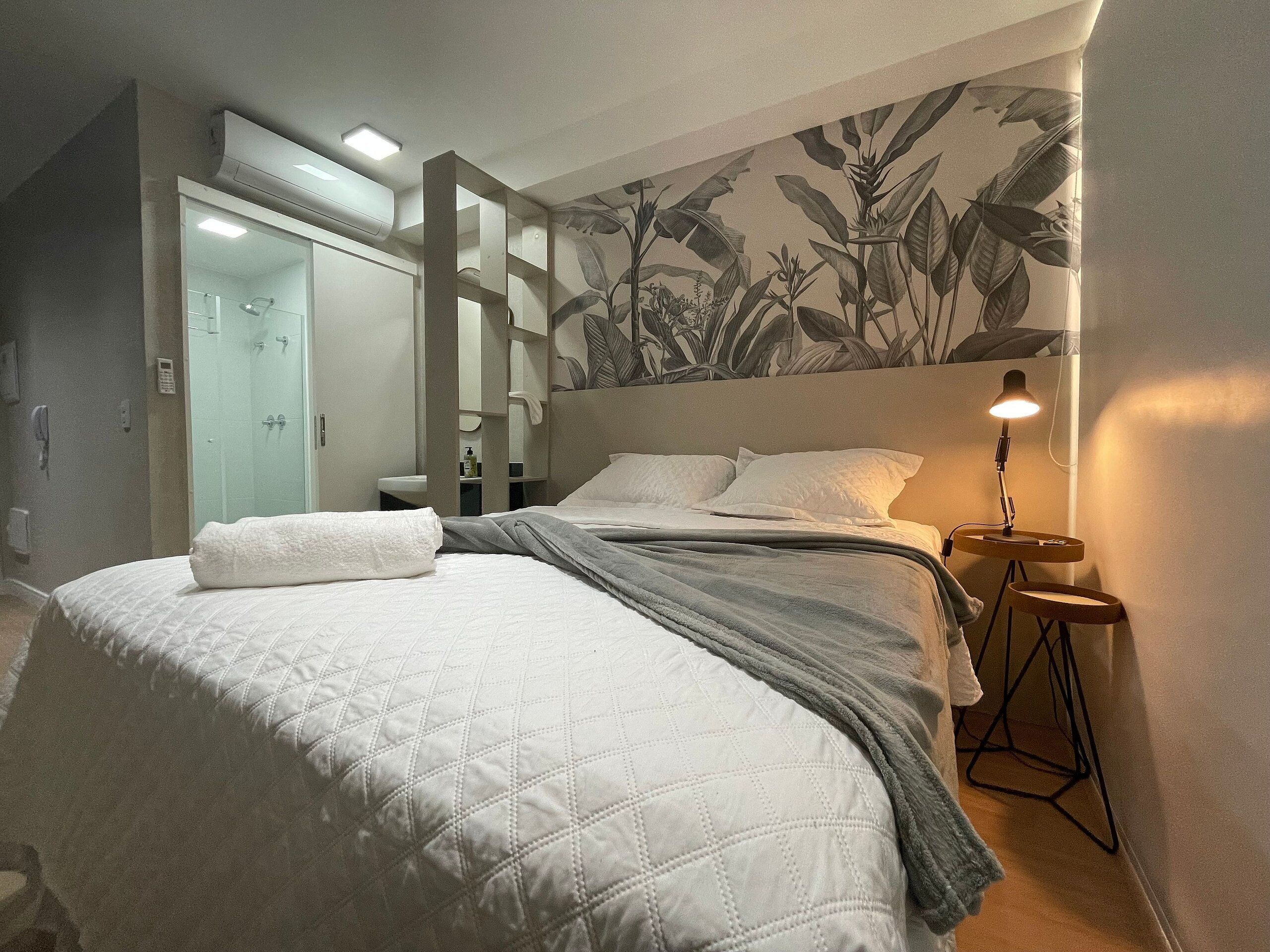 Une chambre d’hôtel avec un lit, une table de chevet, une lampe, une douche et une salle de bain.