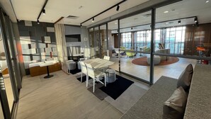 Un interior moderno con un separador de vidrio, muebles blancos y vistas de la ciudad a través de amplias ventanas.
