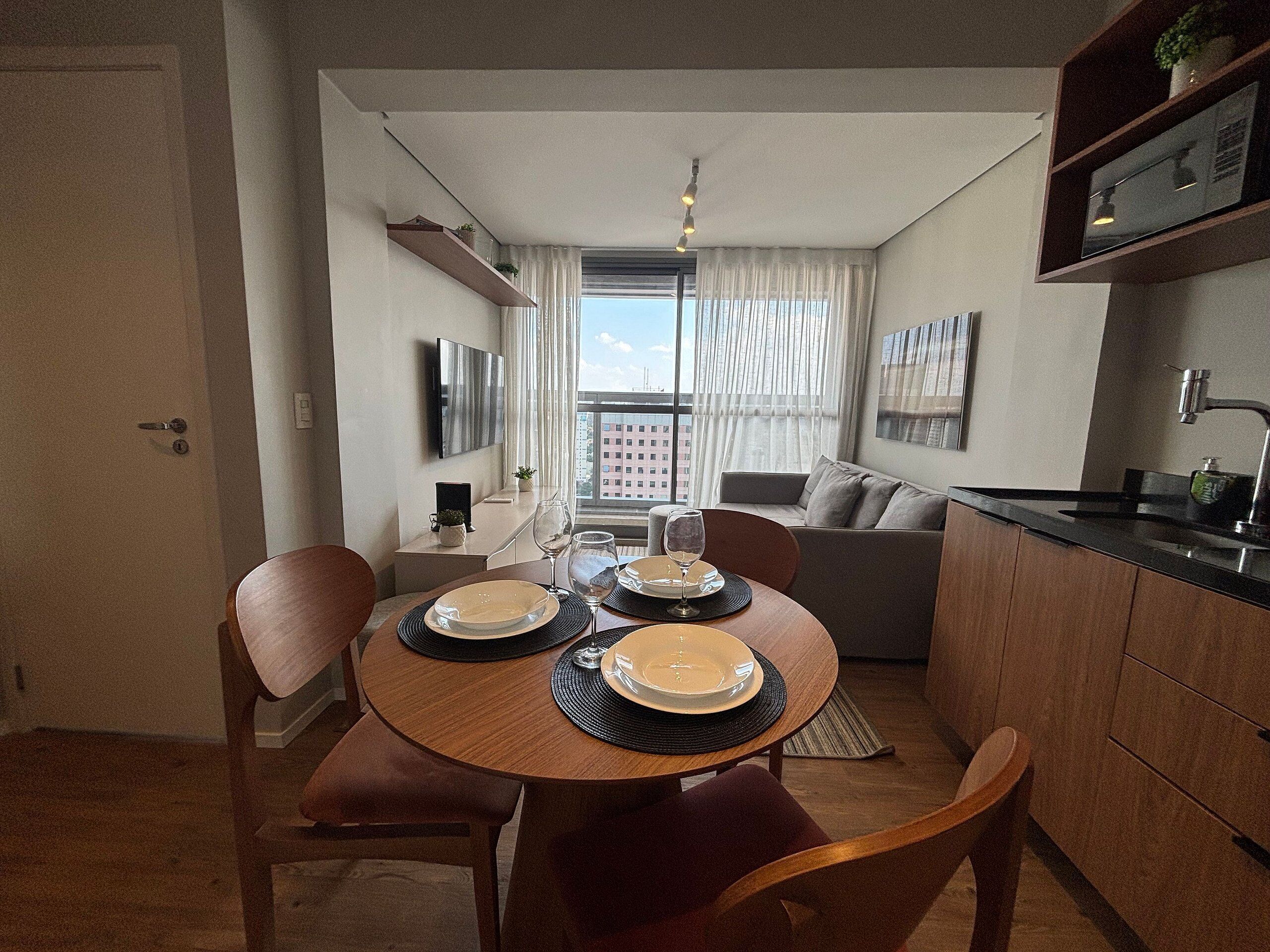 A modern dining area with a round table, chairs, and a kitchen counter.