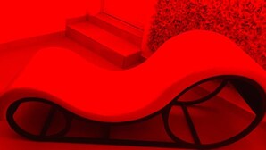 Une sculpture rouge, moderne et abstraite, dotée d’un design incurvé et surmontée d’un escalier menant à sa base.