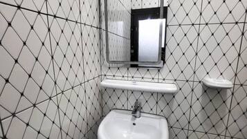 A bathroom with a white sink, a mirror, and a tiled wall with a geometric pattern.