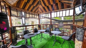 An indoor patio area with wooden beams, stone walls, and artificial grass. - Justina Guest House Hotel  (Douala)