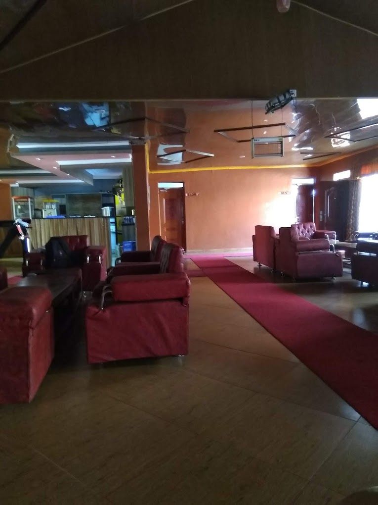 Eine großzügige Lobby mit roter Sitzgelegenheit, einer Bühne und einem sichtbaren Barbereich.