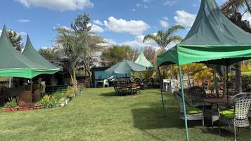 A grassy outdoor area with several green tents and wicker furniture.