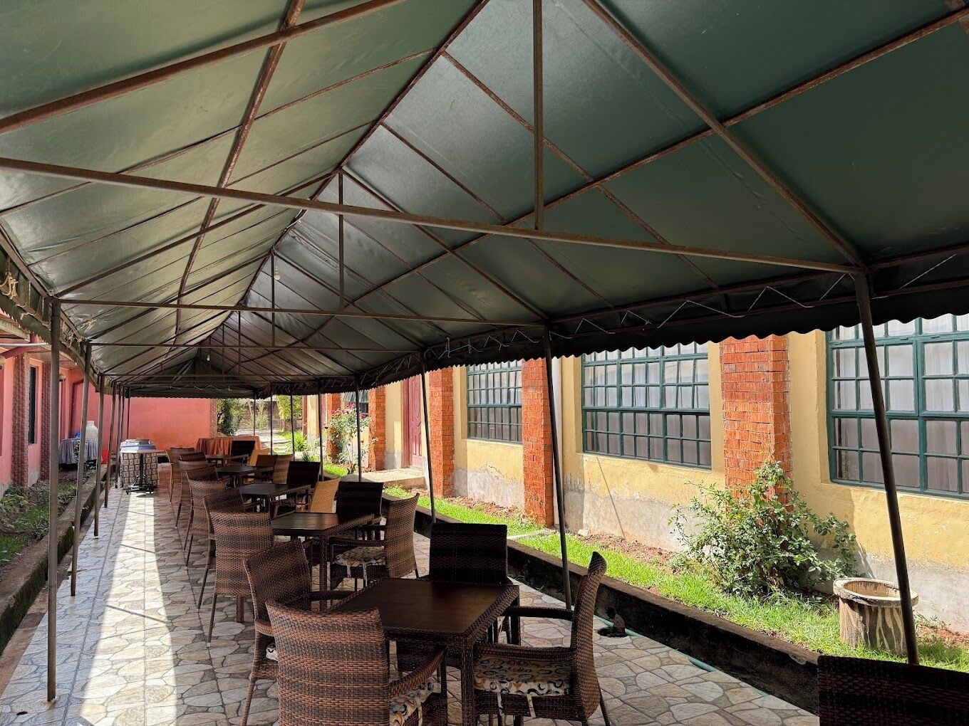 An outdoor covered patio area with tables and chairs, brick walls, and windows.