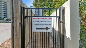 A gated entrance with a sign indicating a private beach walkway for owners and guests only, and a public walkway one block away.
