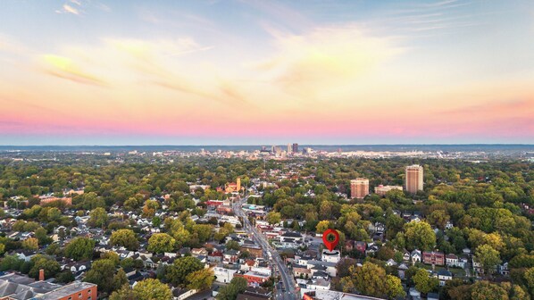 An aerial view of a cityscape with a mix of residential and commercial buildings, a prominent red landmark, and a clear sky at sunset.