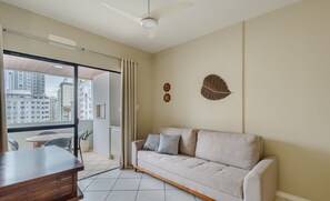 A modern living room with a sofa, a wooden coffee table, and a view of the city through large windows. - Apt w/ Balcony & BBQ 200m From the Beach Rdt1004 (Balneário Camboriú)