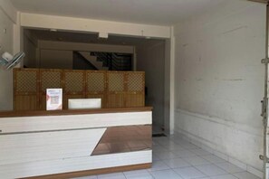 Un área de recepción con mostrador, zona de espera y una escalera al fondo.