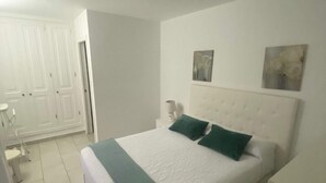 A bedroom with a bed, white walls, and a door.