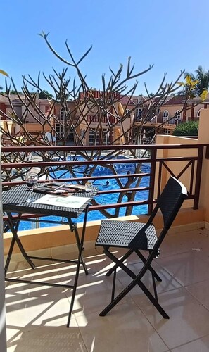 Um terraço com piscina, mesas e cadeiras.