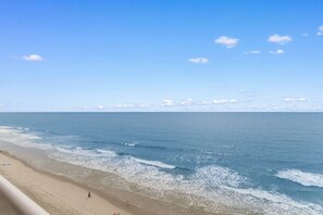 A beach with clear skies and calm waves. - Garden City Beach Oceanfront Condo 902 | Rising Tides Properties Rental (Murrells Inlet)