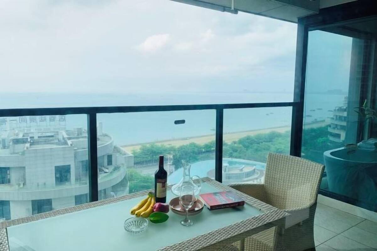Un balcon avec une table dressée pour le dîner, une bouteille de vin et un livre.
