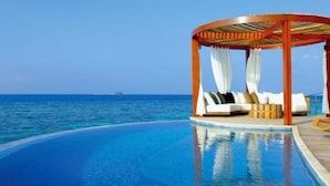 A circular infinity pool with a wooden gazebo and white cushions. - One Room One Car Seaview Holiday Apartment (Beihai)