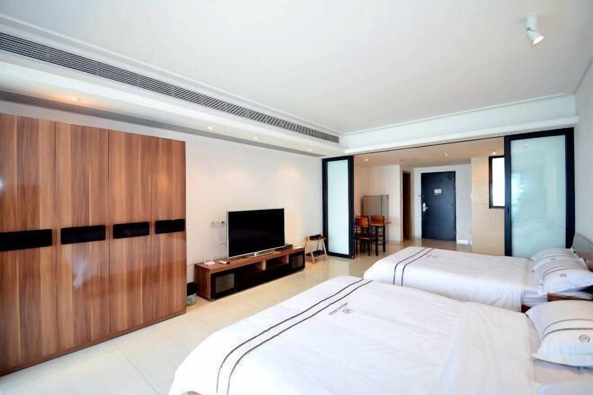 Une chambre d’hôtel avec un grand lit, une télévision, une armoire en bois et un coin repas à l’arrière-plan.