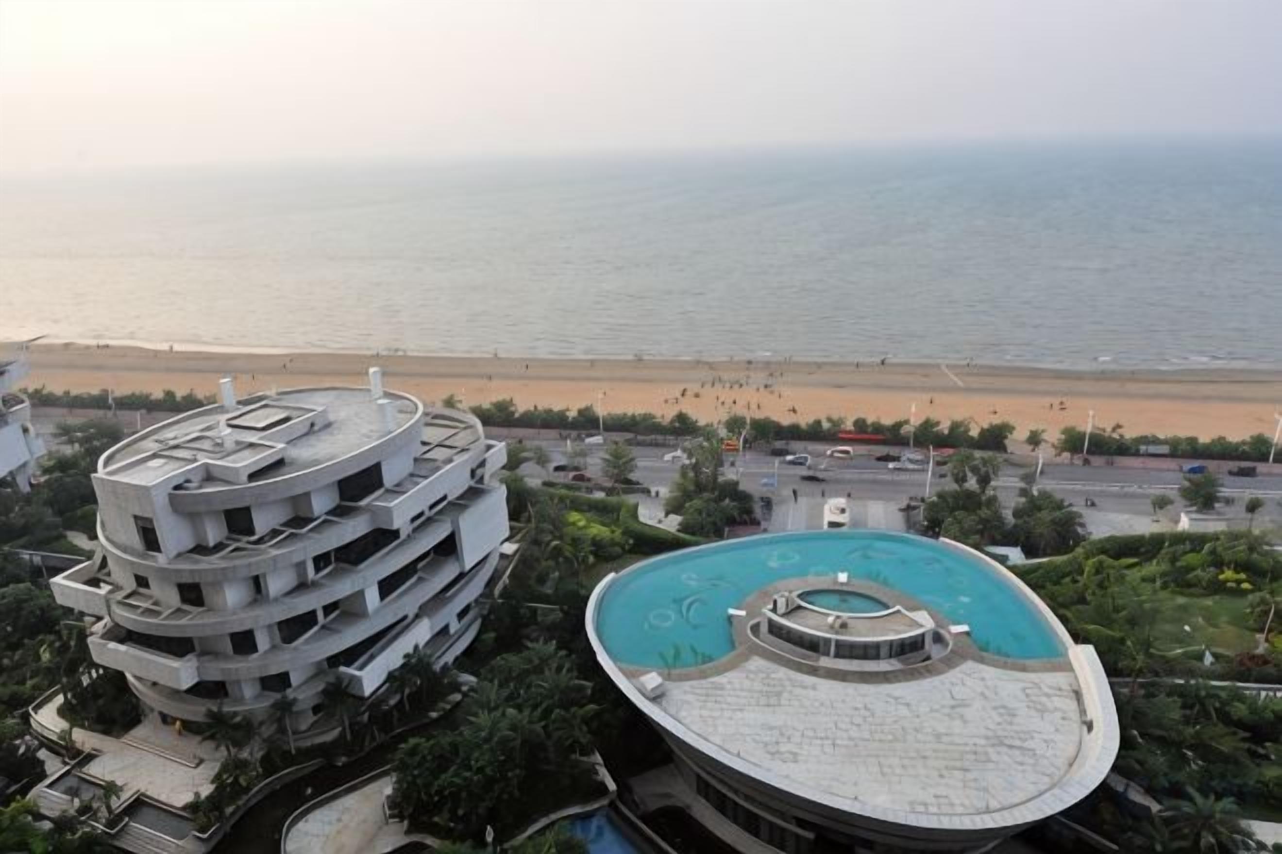 Edifício com vários andares, piscina no terraço e vista para a praia.