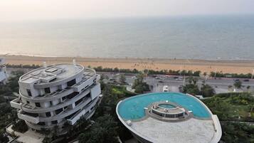 Edifício com vários andares, piscina no terraço e vista para a praia.