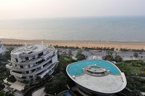 Ein mehrstöckiges Gebäude mit Pool auf dem Dach und Blick auf den Strand.