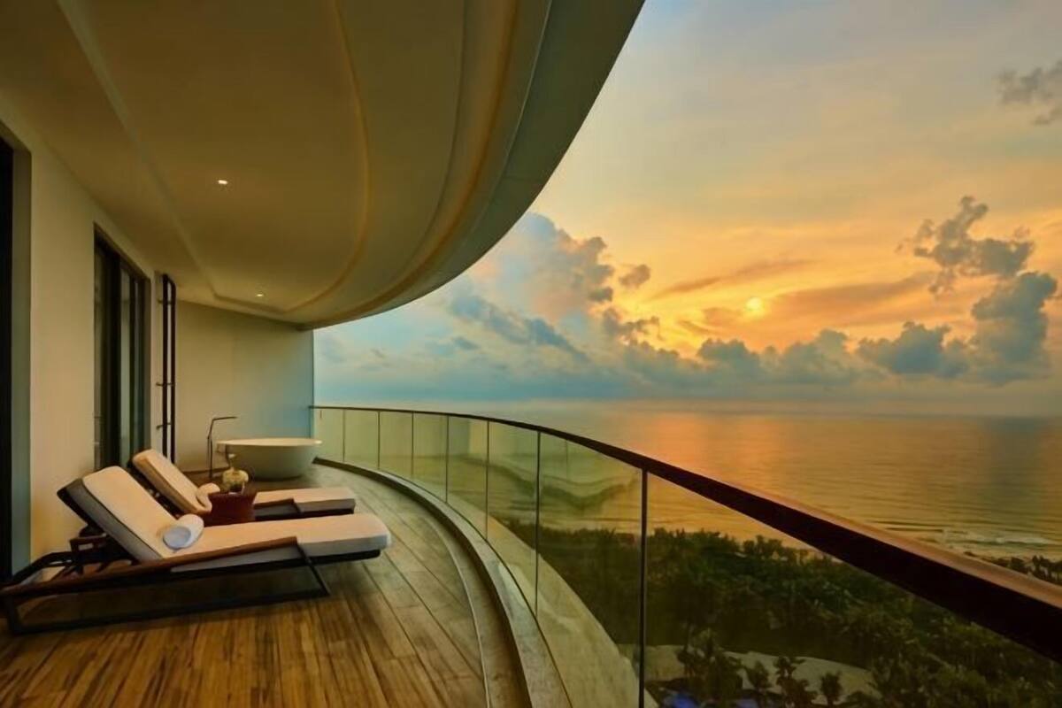 Un balcon doté d’une balustrade incurvée, donnant sur une étendue d’eau au coucher du soleil.