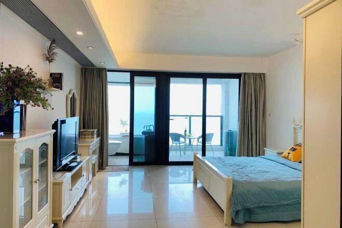 Une chambre d’hôtel moderne équipée d’un lit, d’une télévision, d’un balcon avec vue et d’un coin repas.