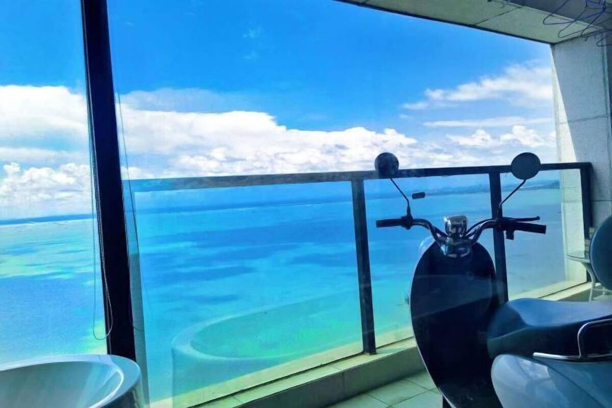 Un balcon offrant une vue dégagée sur l’océan et un scooter.