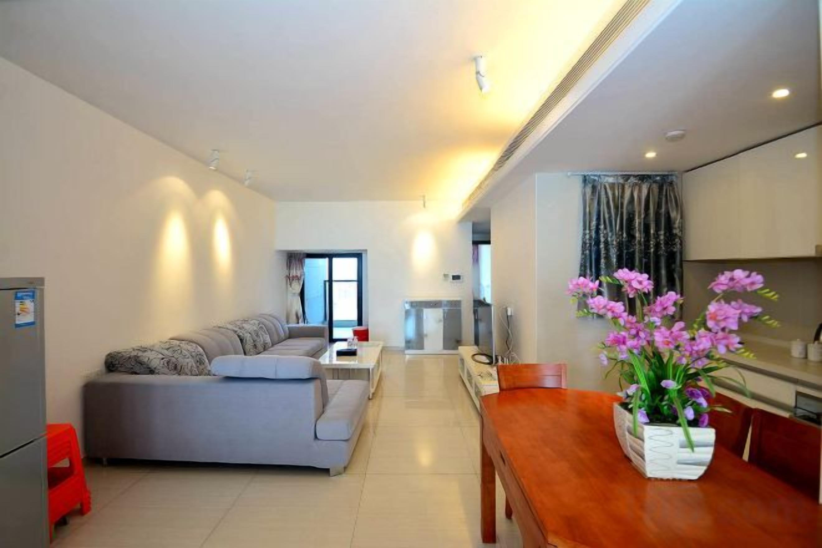A modern living room with a sofa, dining table, and a vase of flowers.