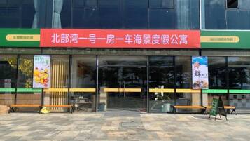 A building with a red sign, glass doors, and a bench outside.