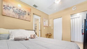 A bedroom with a bed, a painting of zebras, a mirror, a door, and a refrigerator. - Modern comfortable close to the beach/airport (Fort Lauderdale)