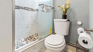 A bathroom with a toilet, a glass shower enclosure, and a small potted plant on the wall. - Modern comfortable close to the beach/airport (Fort Lauderdale)